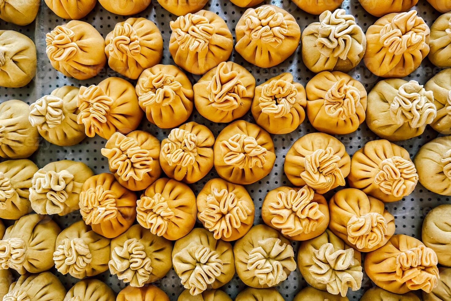 yellow dumplings neatly arranged on a tray in a bustling market during midday photo
