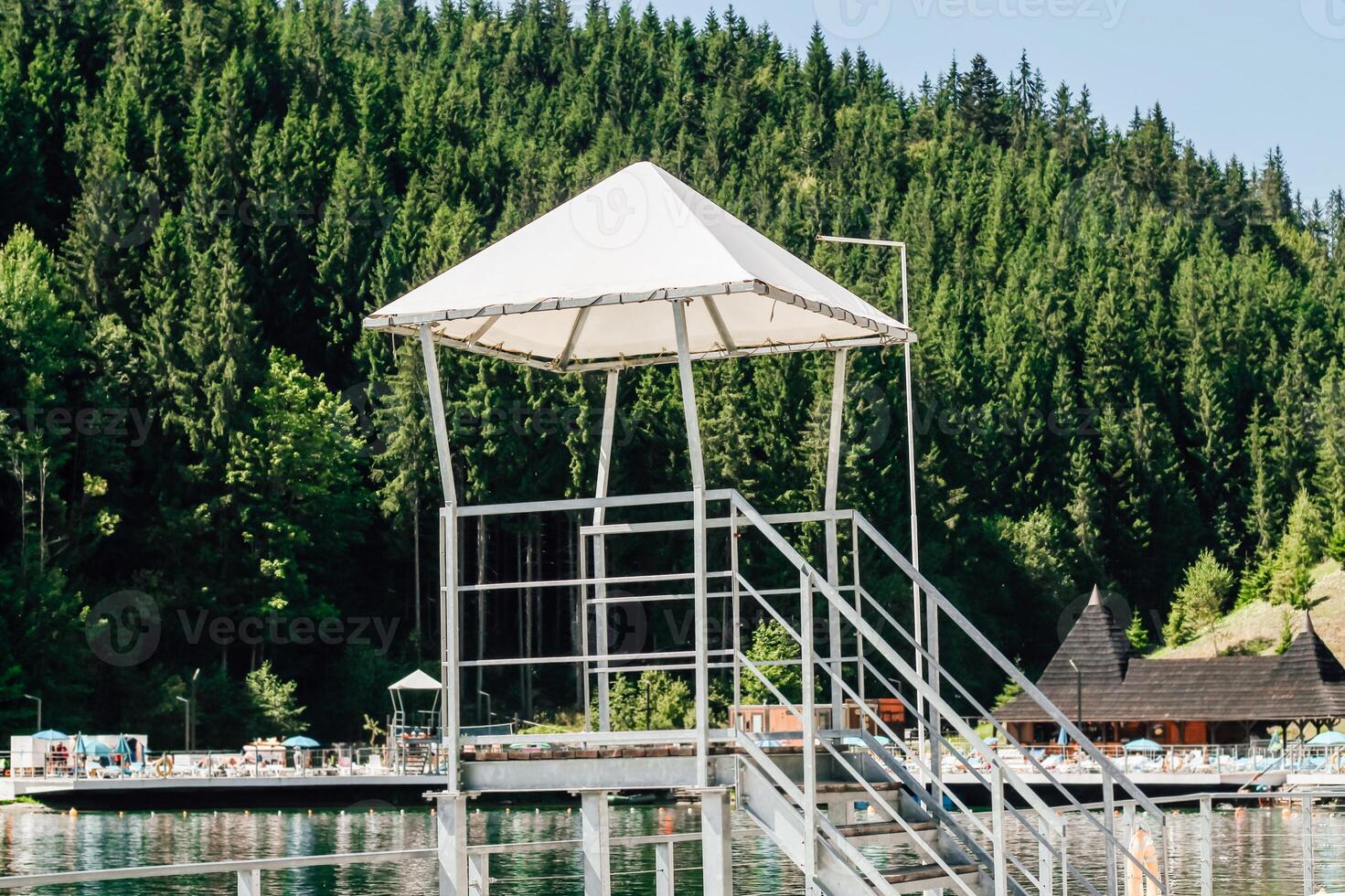 Lifeguard tower overlooking a tranquil lake surrounded by lush greenery during summer photo