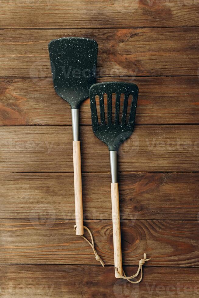Cooking utensils including spatula and slotted turner on wooden table surface photo