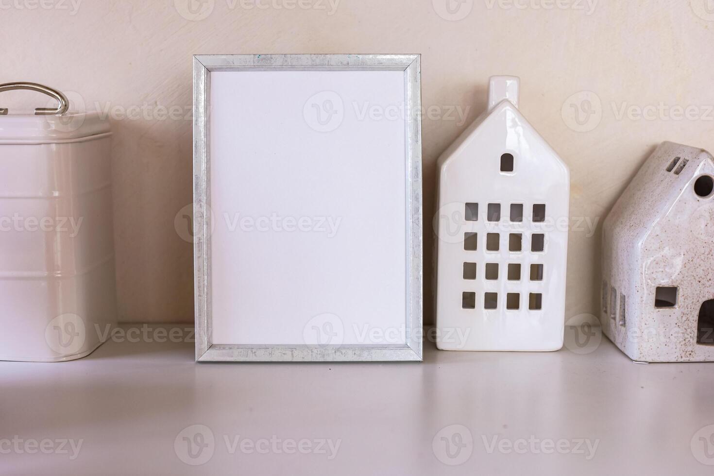 Blank picture mockup frame and decorative ceramic houses on a wooden table photo