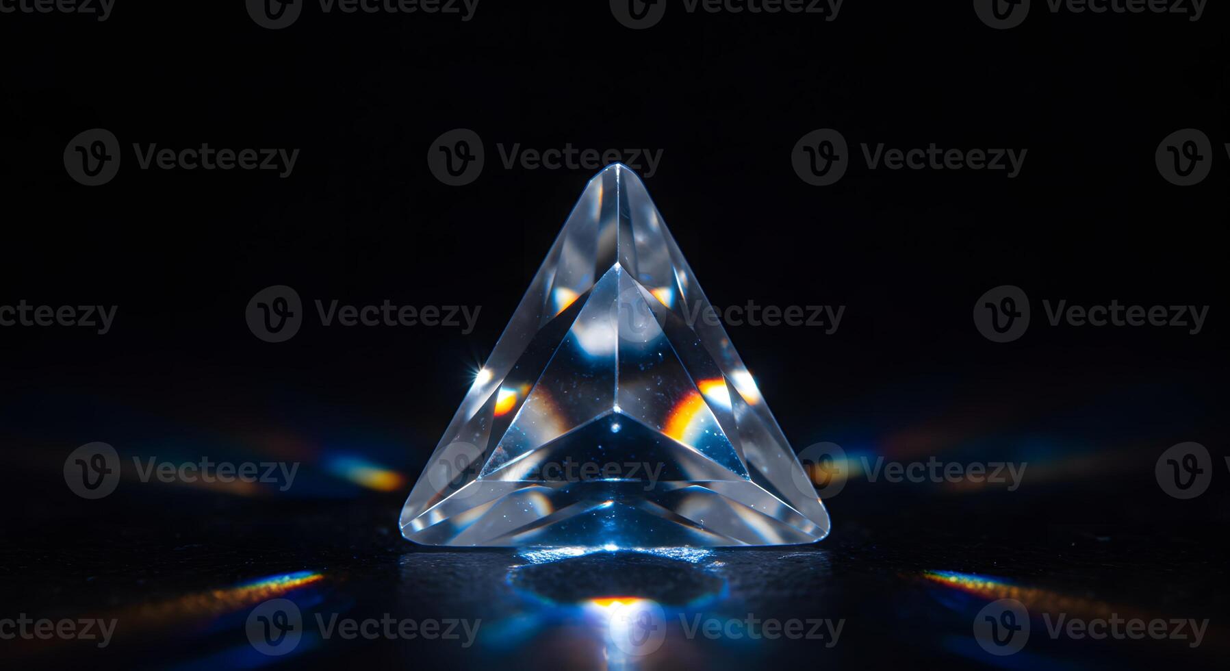 A clear, triangular prism rests on a black surface, scattering light and creating rainbow reflections. photo