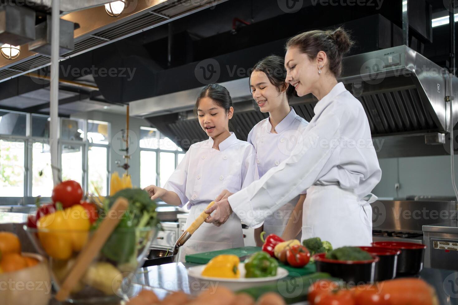 Professional chef is teaching young culinary class student to prepare fresh ingredient for the meal inside the restaurant kitchen for fine dining gourmet and cooking school photo