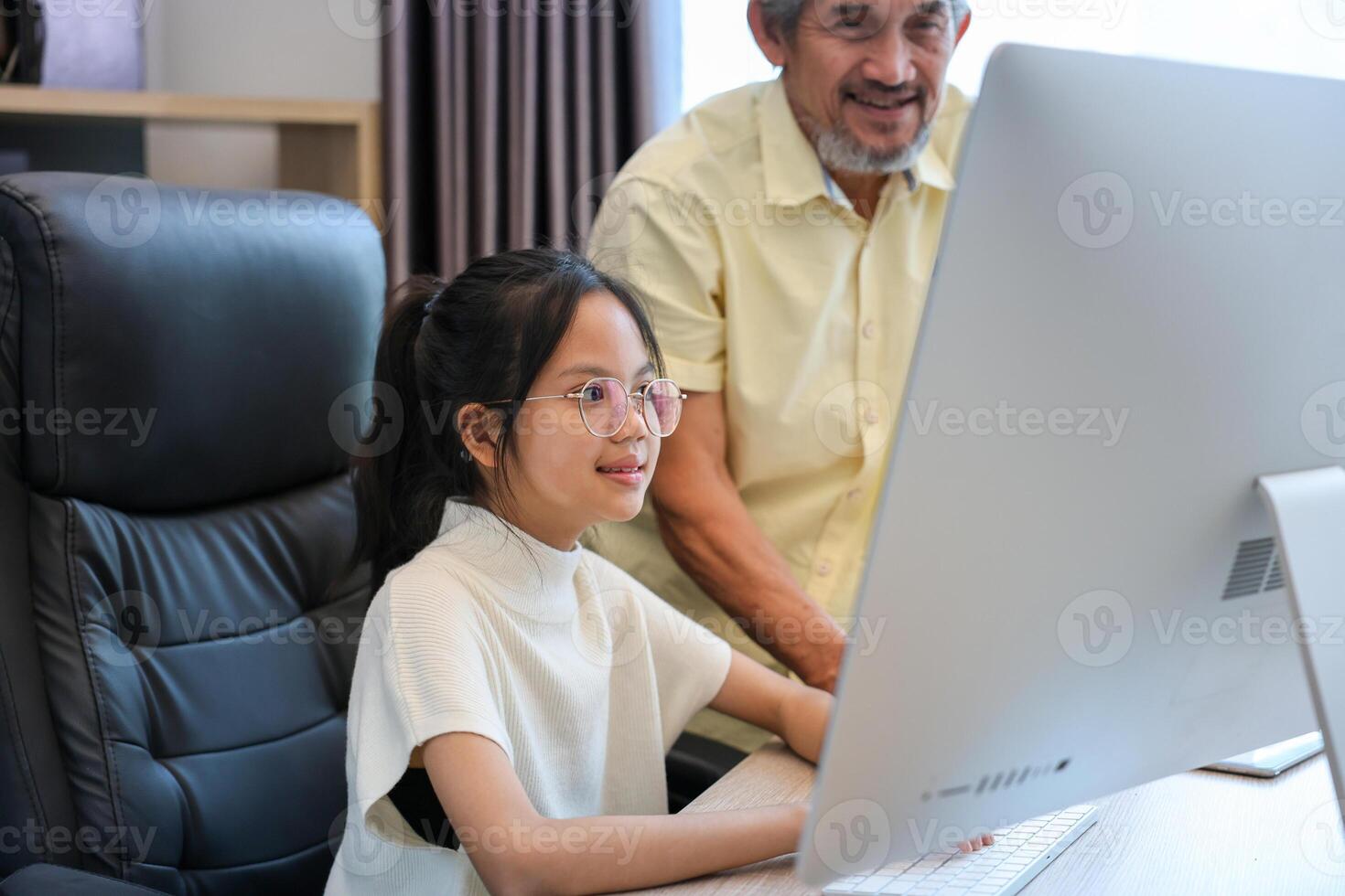 Young asian schoolgirl is doing class homework assignment at home with grandfather advice for education and study photo