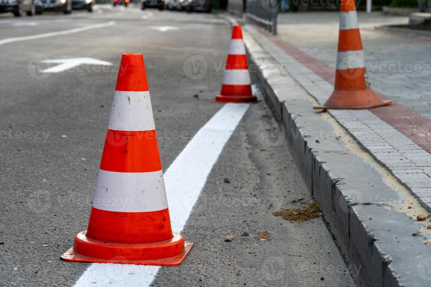 Traffic cones line the street, indicating ongoing construction work. Vehicles are rerouted while new boundaries are being established in an urban neighborhood photo
