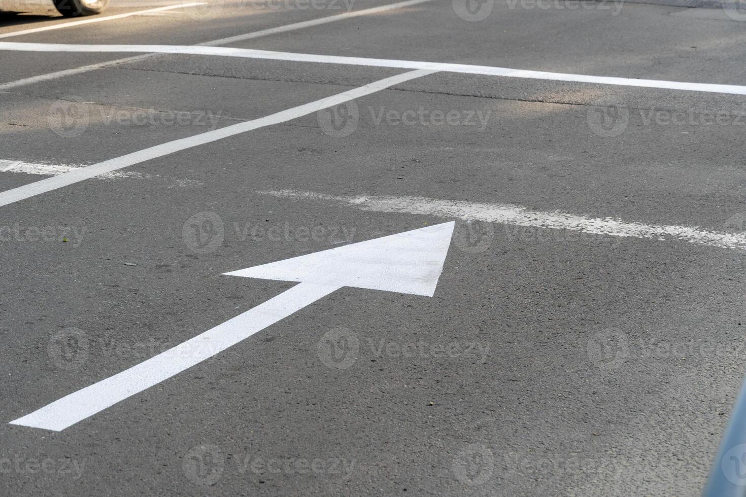 A clear view of white road markings on asphalt shows directional arrows and lines guiding vehicles. This image captures a well-maintained urban street scene photo