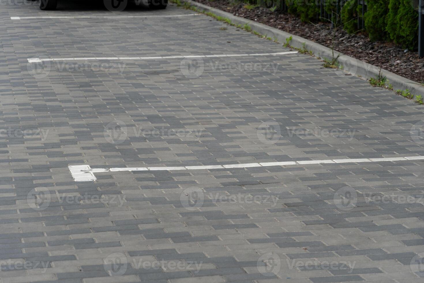 Unoccupied parking lot features outlined spaces on a paved surface, showcasing a clean and quiet urban environment with patches of grass along the edges photo