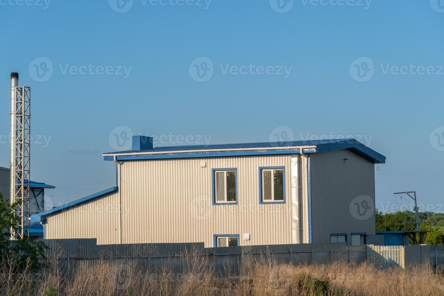 Modern structure designed with principles stands in a rural area under evening light, contrasting with soft grassland and clear blue skies photo