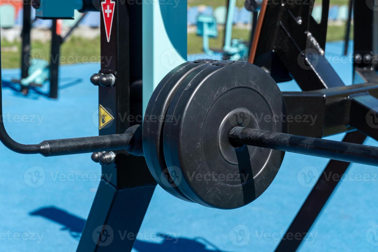 Advanced strength training apparatus featuring weights attached, situated in a lively outdoor gym environment surrounded by colorful landscapes photo