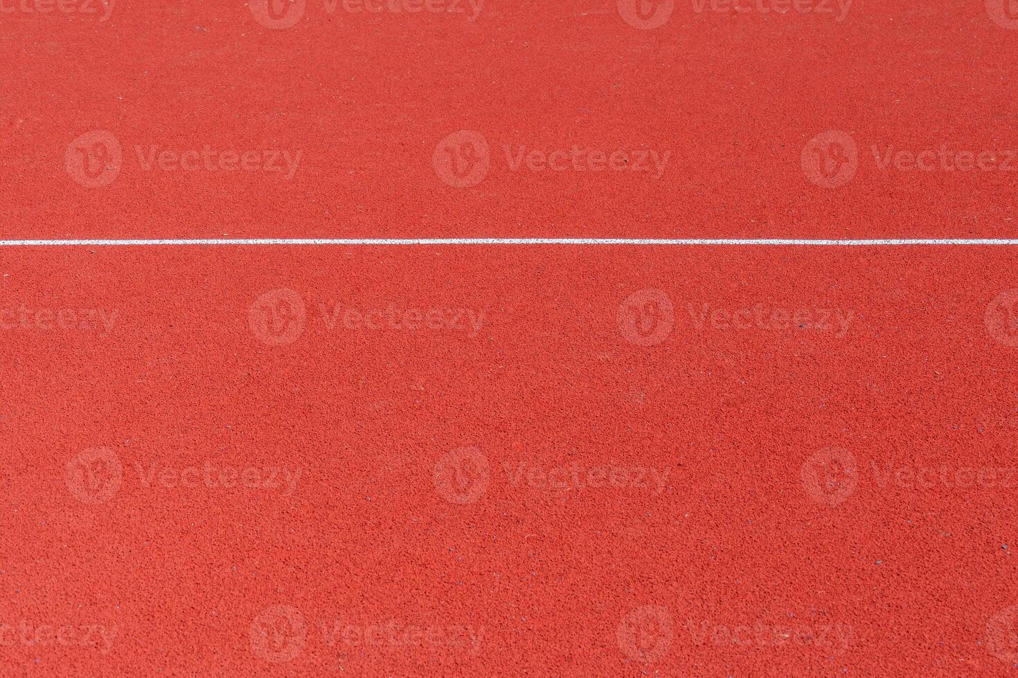 A vibrant red surface designed for athletic activities highlights the area where runners will compete. This track is suitable for various sports events photo