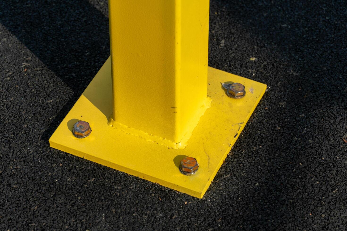 A yellow pole with nuts and bolts on it photo