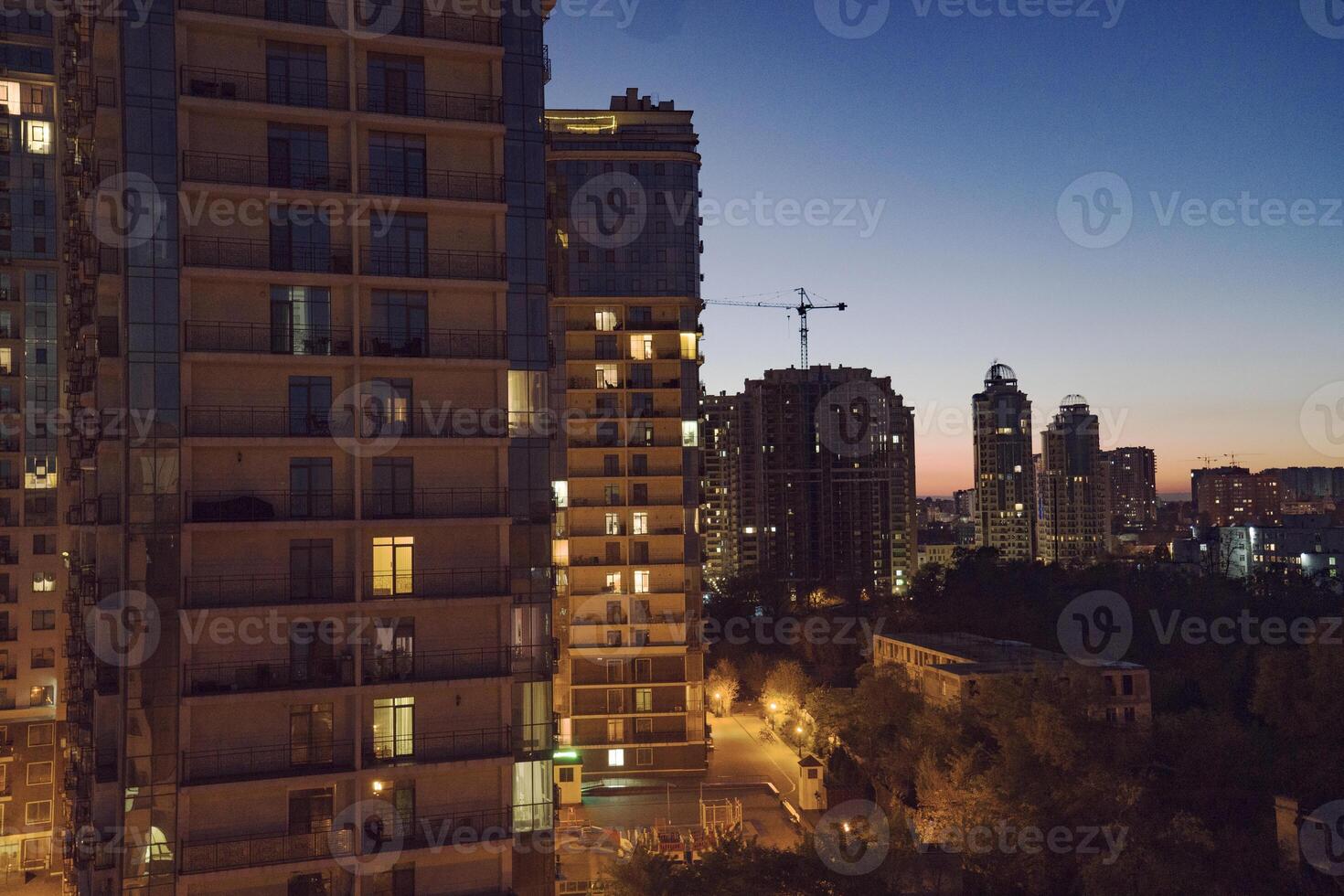 Urban skyline at dusk featuring modern high-rise buildings illuminated by warm lights, with a serene atmosphere and a hint of twilight in the background showcasing city life photo
