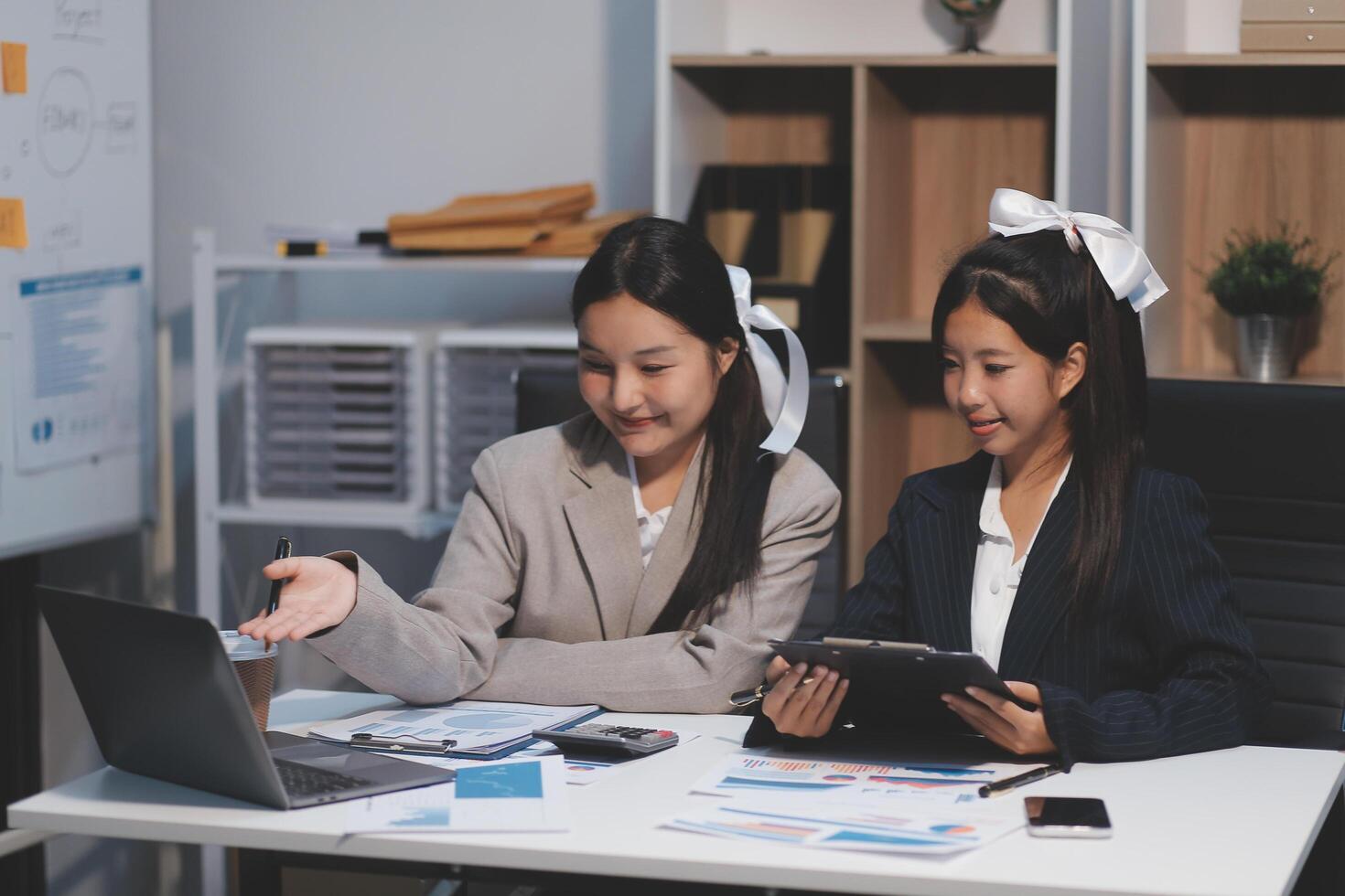 Two asian girls sitting at a desk with a laptop photo