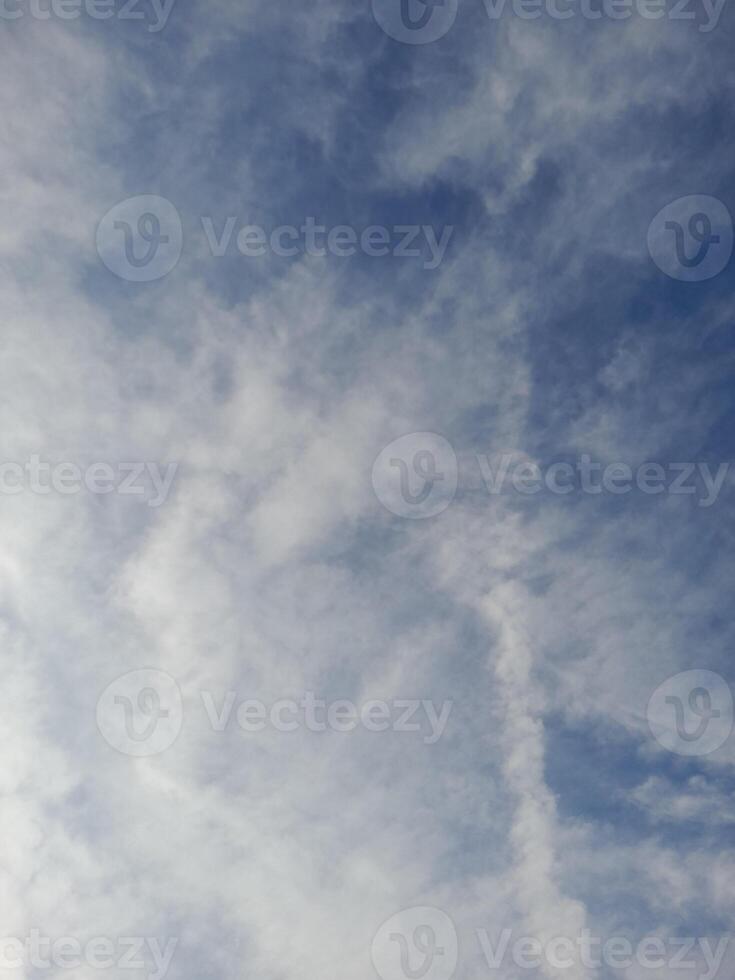 Soft, wispy clouds stretch across a pale blue sky, creating a peaceful and serene atmosphere with gentle light and subtle textures. photo