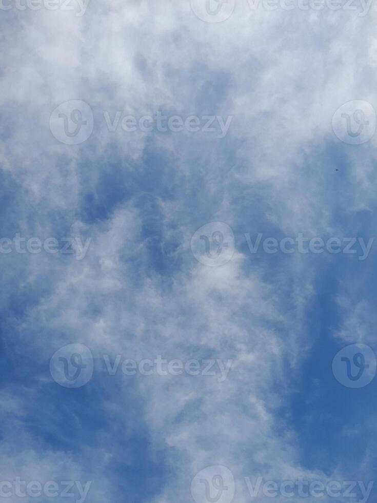 Light blue sky with soft, scattered cirrus clouds creating a wispy and textured appearance across the sky. photo