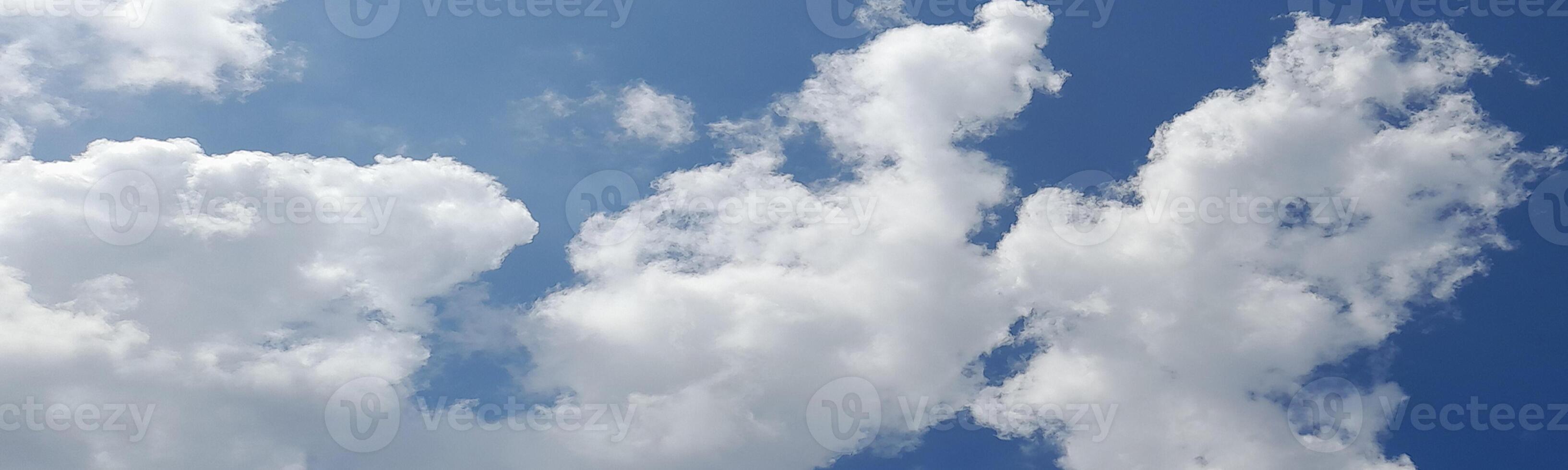 Bright blue sky with fluffy white clouds scattered across, creating a peaceful and sunny daytime atmosphere. photo