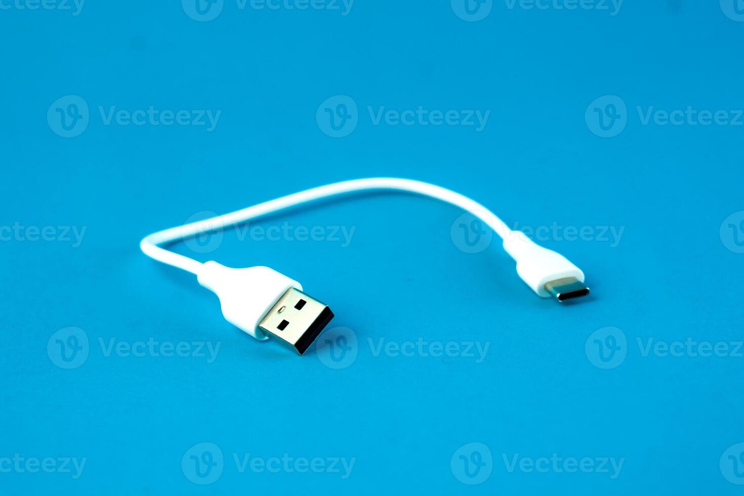 A short white USB to micro-USB cable on a blue background. Ideal for charging and data transfer for smartphones, tablets, and electronic devices. Compact and portable for everyday use. photo