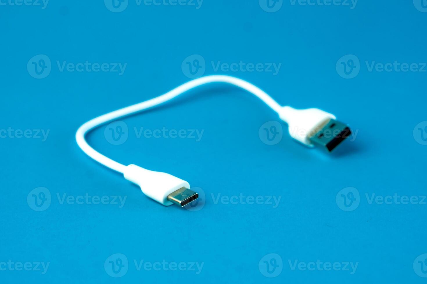 A short white USB to microUSB cable on a blue background. Ideal for charging and data transfer for smartphones, tablets, and electronic devices. Compact and portable for everyday use. photo