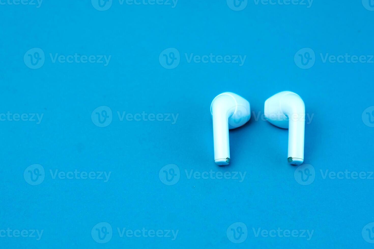 A pair of modern wireless earbuds on a vibrant blue background. Stylish and compact Bluetooth earphones designed for high-quality audio, seamless connectivity, and everyday convenience. photo