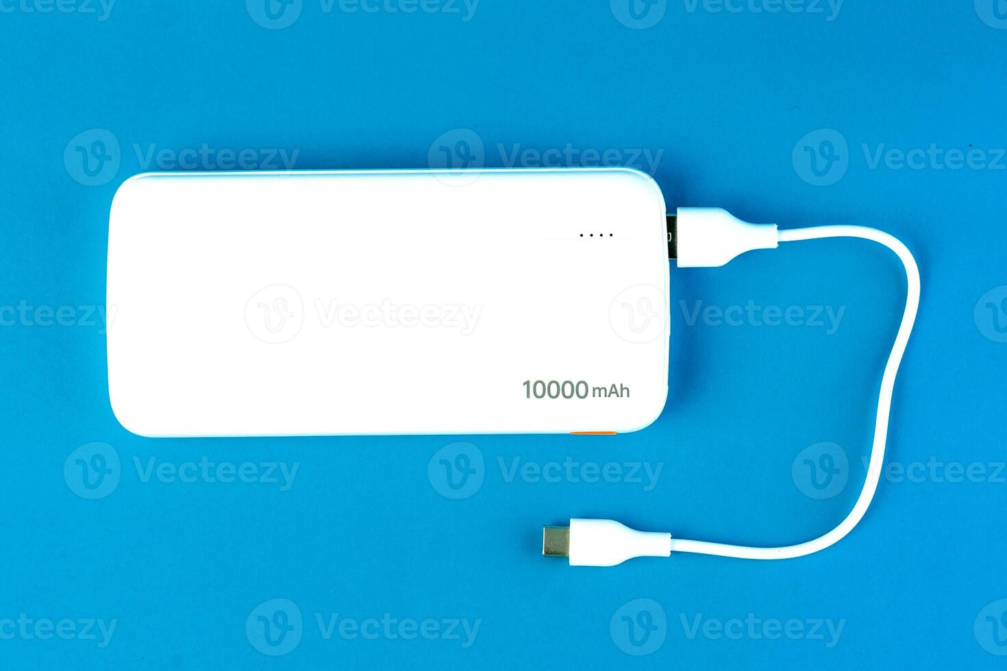 White 10000mAh power bank with a USB charging cable on a blue background. Ideal for fast charging smartphones, tablets, and electronic devices. Portable and compact for travel use photo