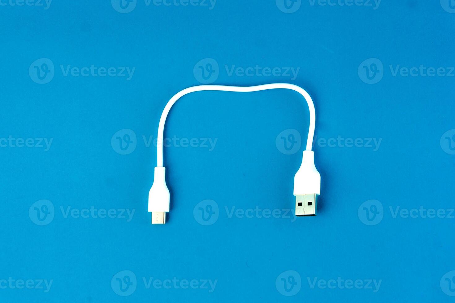 Short white USB to micro-USB cable on a blue background. Ideal for charging and data transfer for smartphones, tablets, and electronic devices. Compact and portable for everyday use. photo