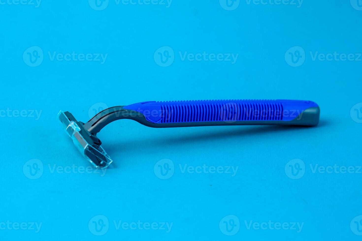 Blue disposable razor with a protective cap placed on a bright blue background. The ergonomic handle and sharp blade make it ideal for shaving facial or body hair safely and smoothly photo