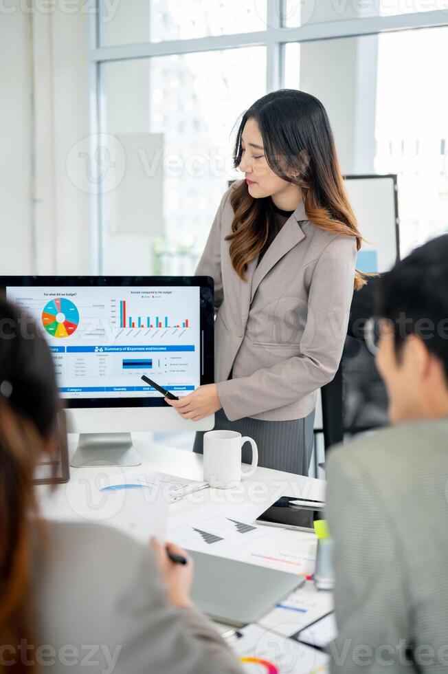 Businesswoman or female office worker is pointing at monitor and explaining a report to her coworker photo