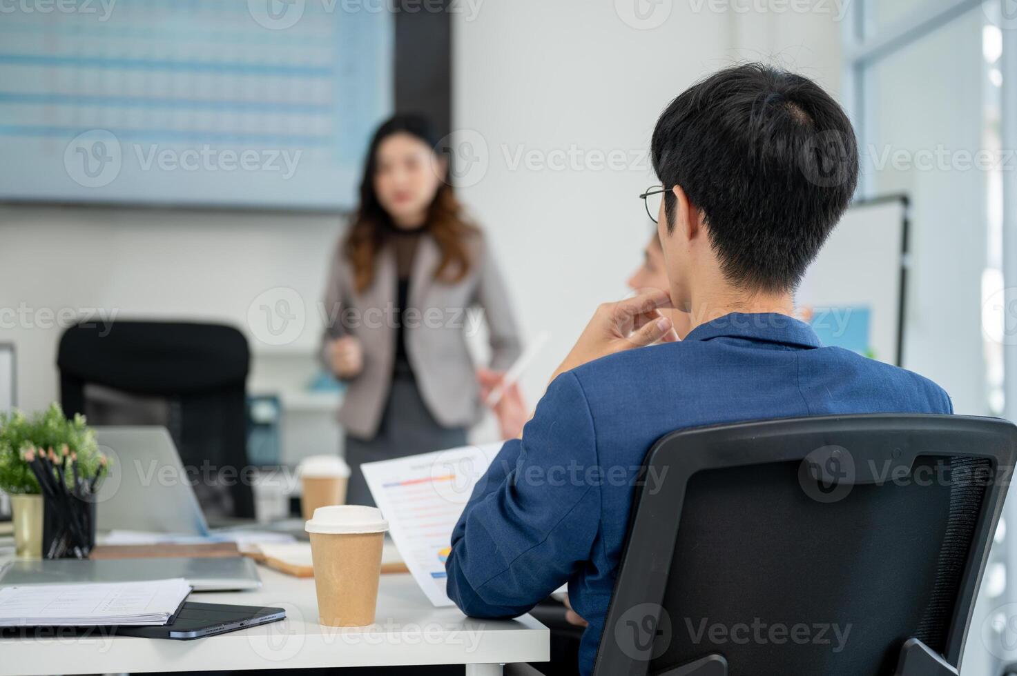 Back view of businessman or office worker holding document and look at female coworker in a meeting photo