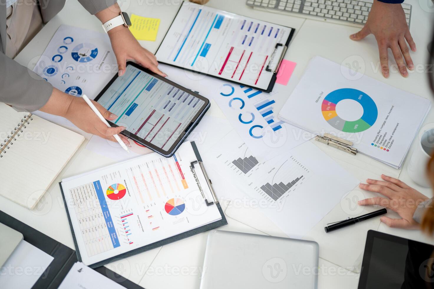 Top view of a working desk with a pair of hand holding a digital tablet and scattered documents. photo
