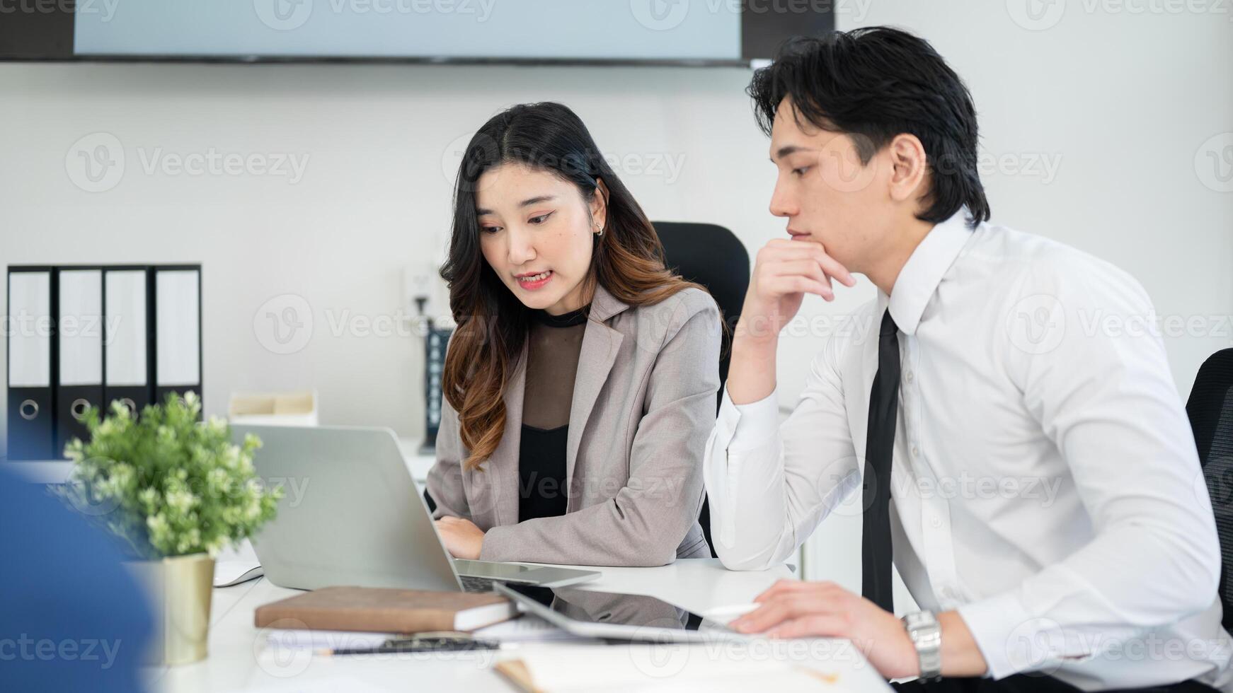 Female office worker is explaining data on her laptop to male coworker. business meeting or planning photo