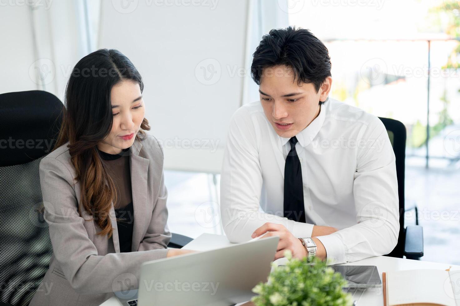 Female office worker is showing and explaining the business data on laptop to her male coworker. photo