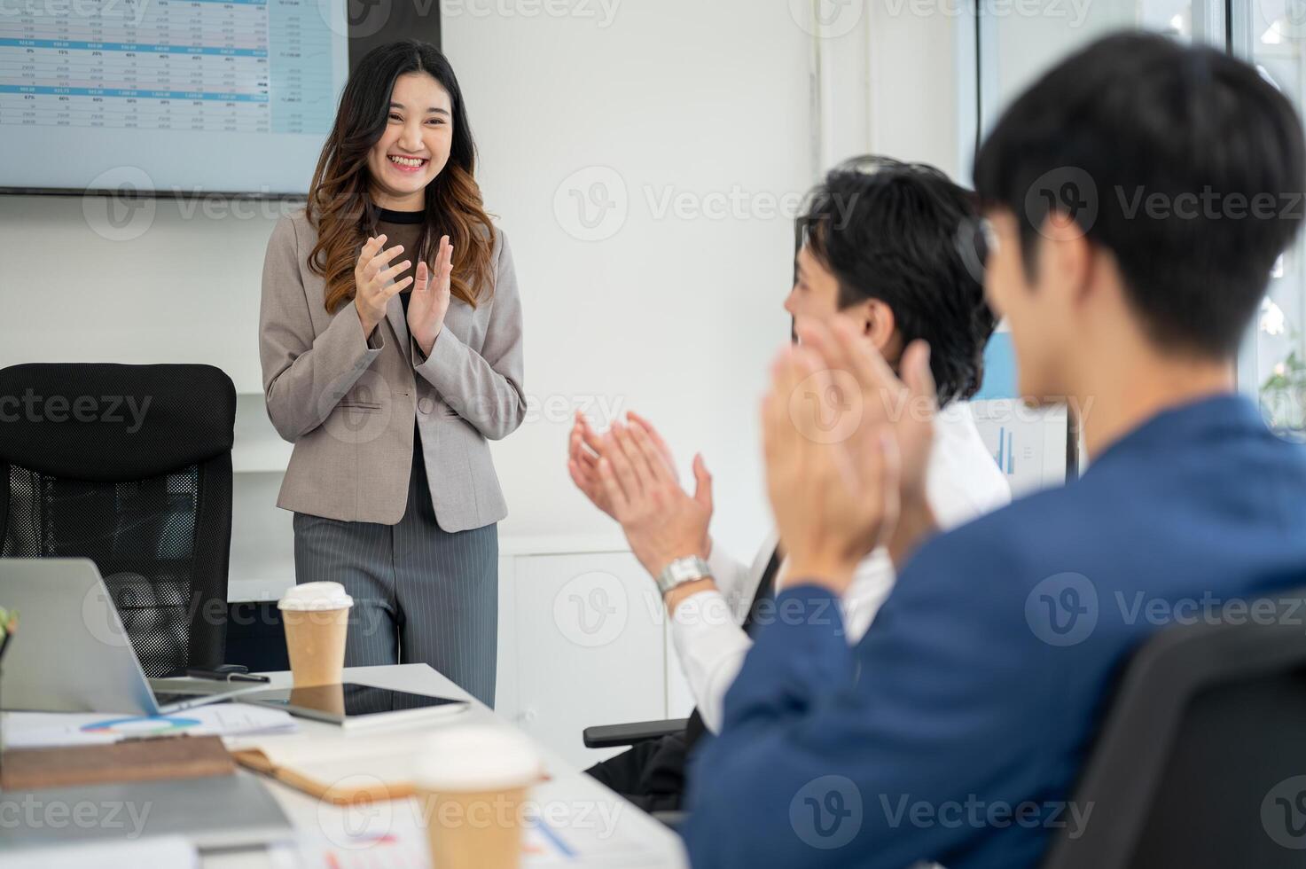Businesswoman or female office worker is smiling while standing and clapping hands with coworkers. photo