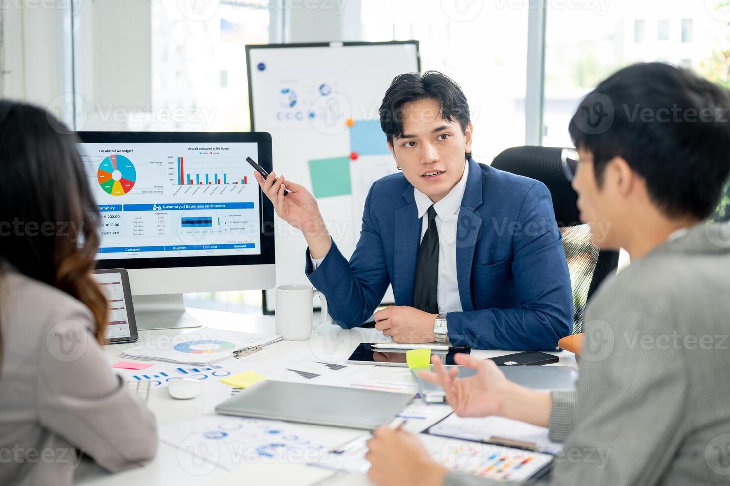 Businessman or male office worker is explaining the financial report on monitor his coworkers. photo