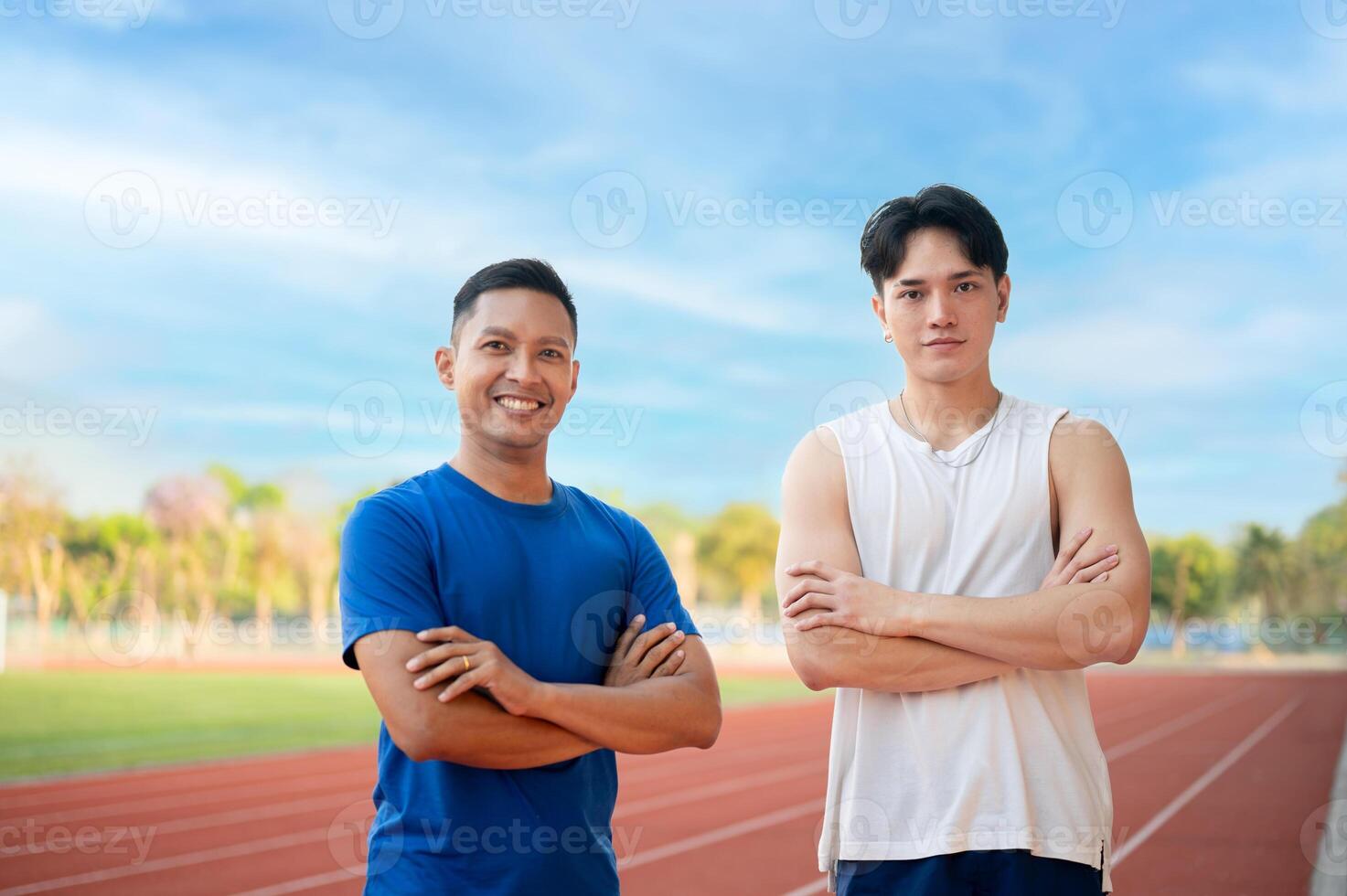 Two asian athlete men are standing with arms crossed, Posing and looking at camera on the racetrack. photo