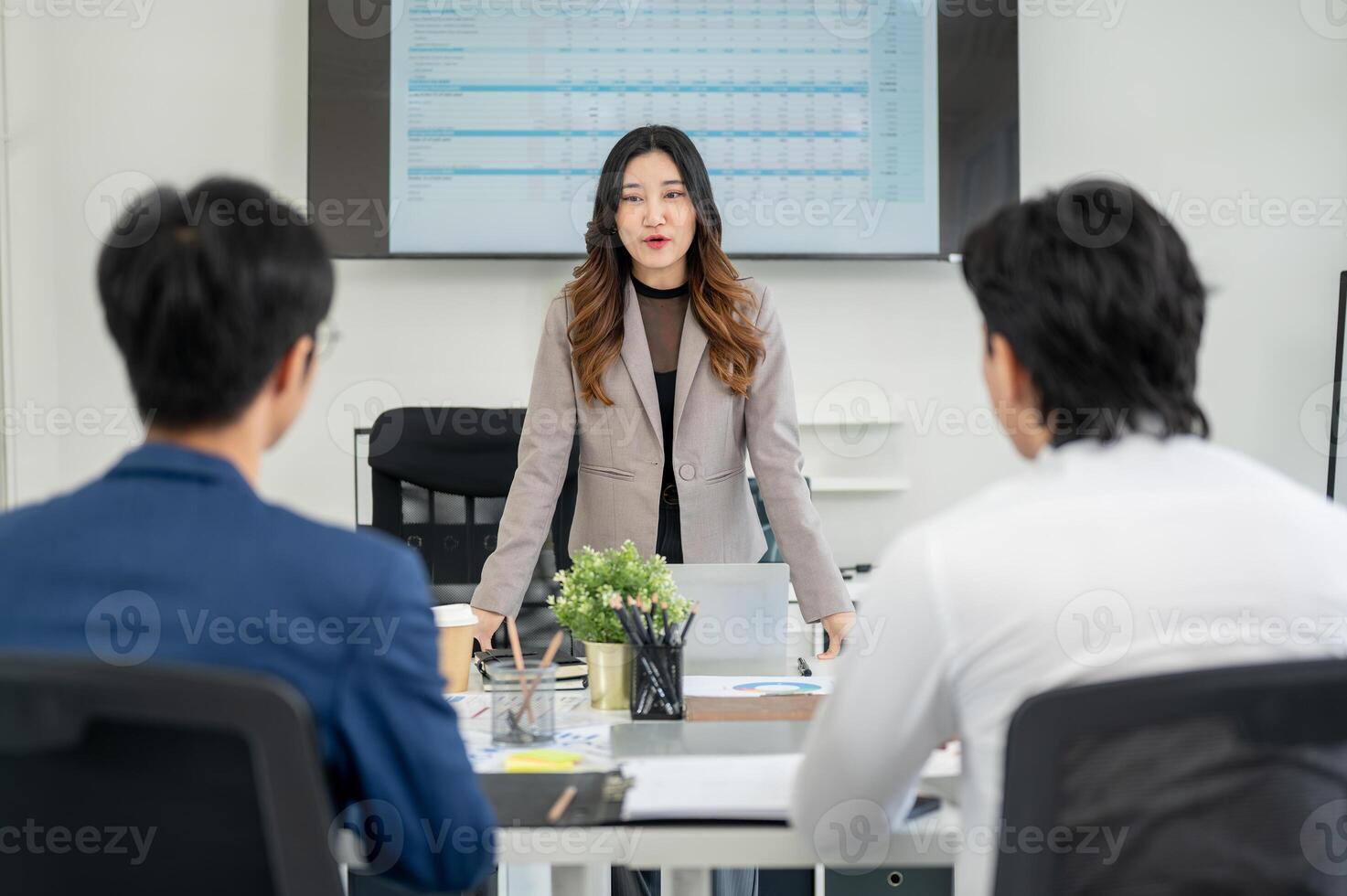 Businesswoman or female office worker is standing in front of a monitor and speaking in a meeting. photo