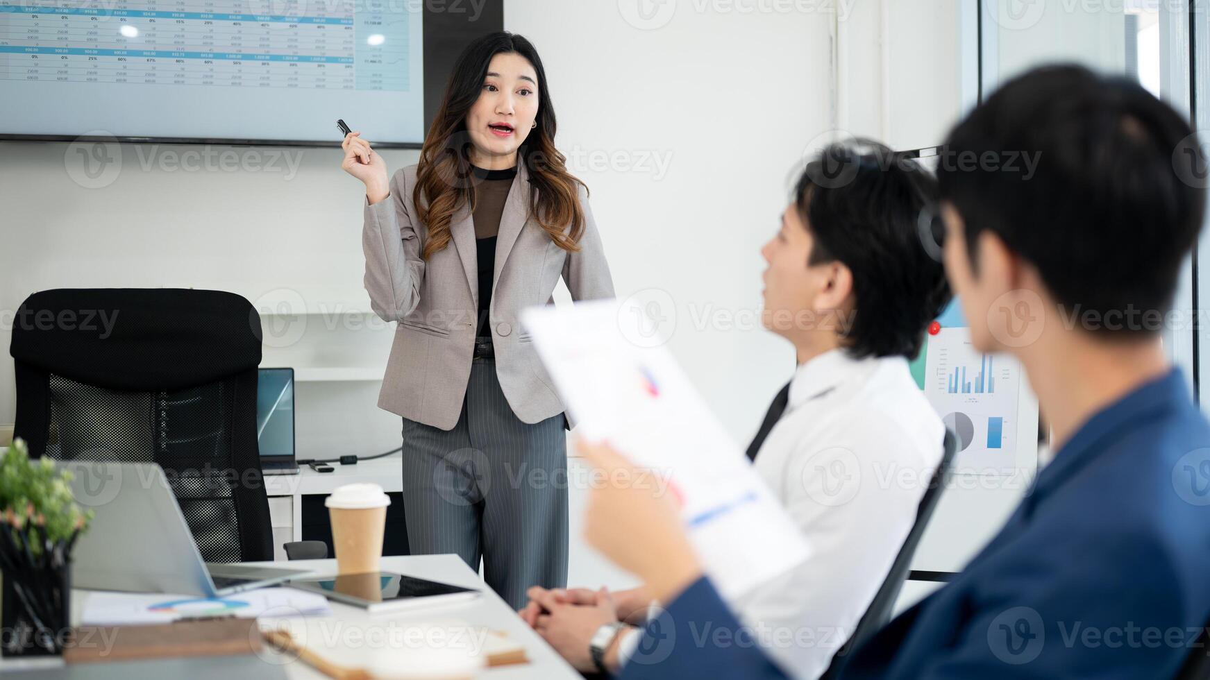Businesswoman or female office worker is explaining datas on monitor to male coworkers in a meeting. photo