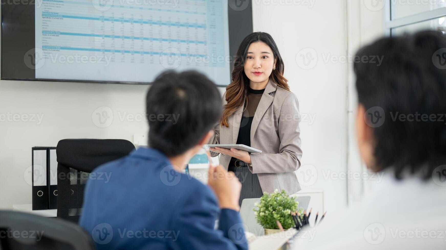 Businesswoman or female office worker holding digital tablet while speaking to a coworker in meeting photo
