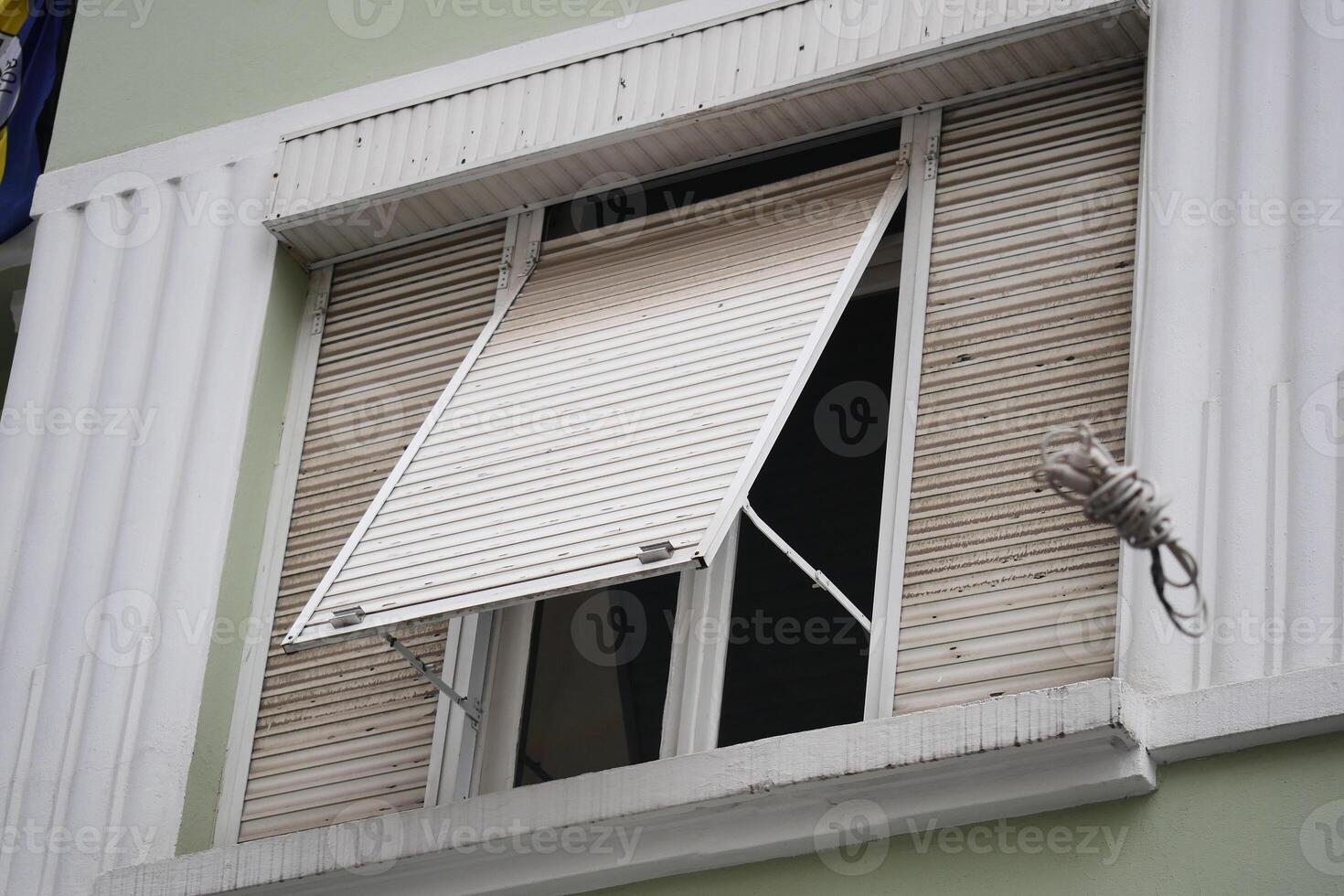Blinds partially opened at apartment window on bright day photo