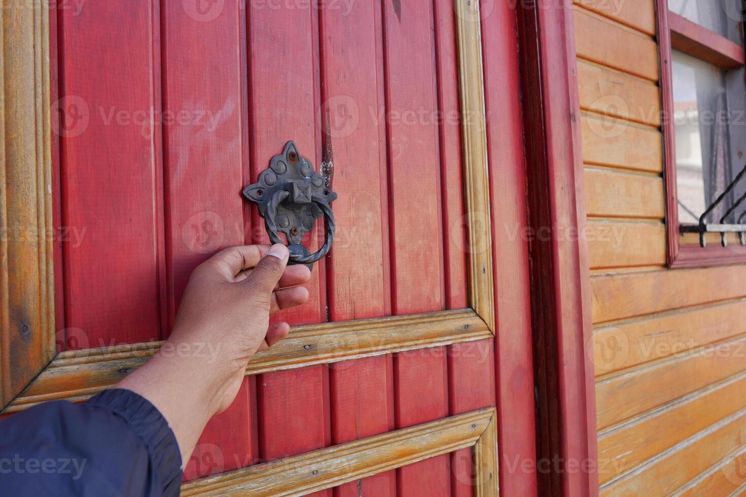 Hand reaching for door knocker on wooden door photo