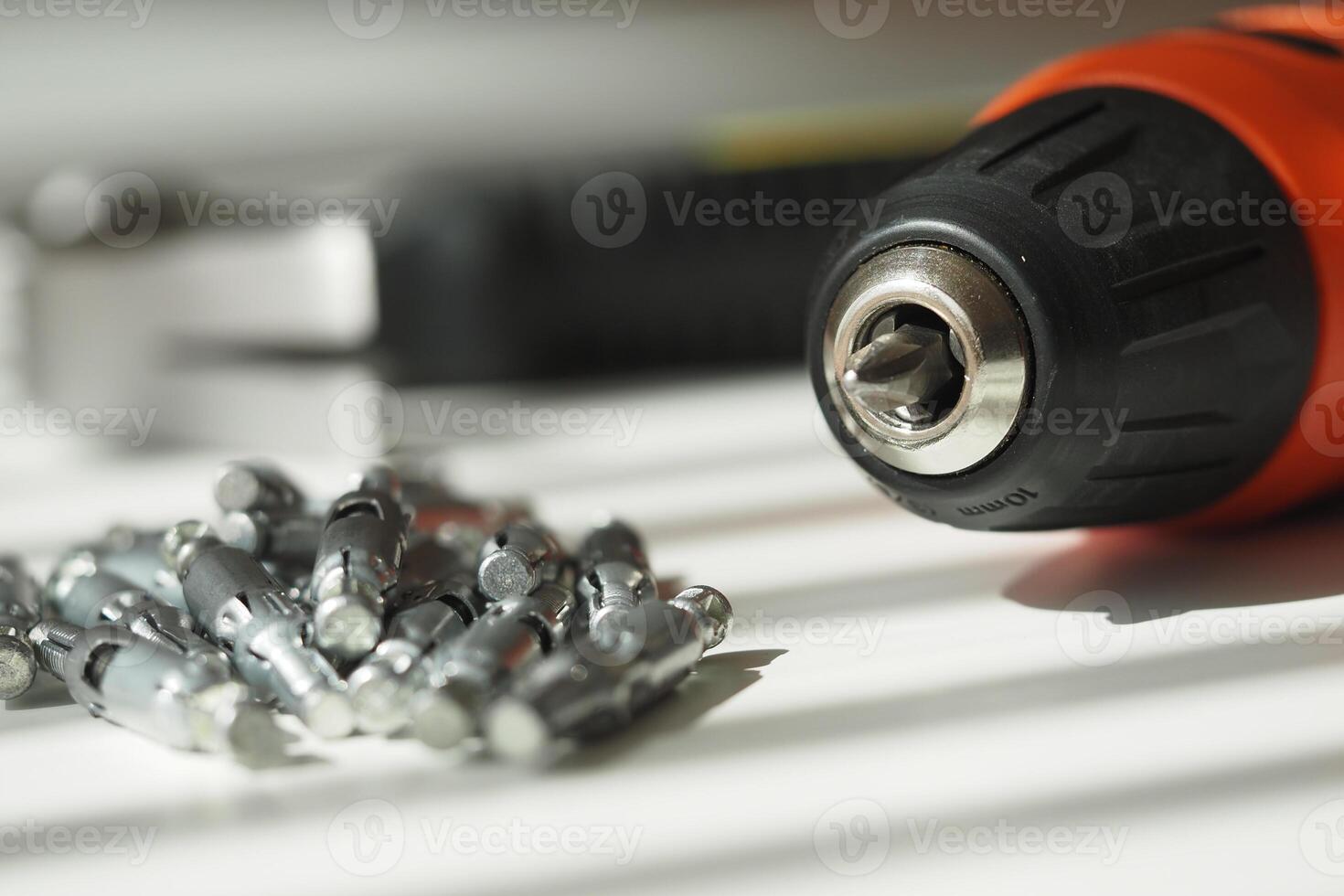 Close-up of a power drill and screws on a work surface photo