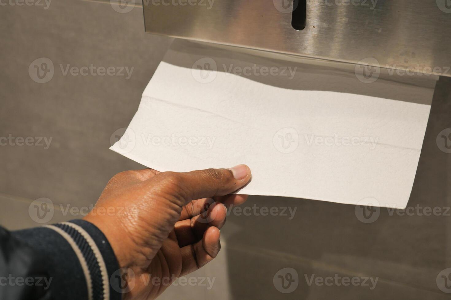 Hand reaching for paper towel in a restroom photo