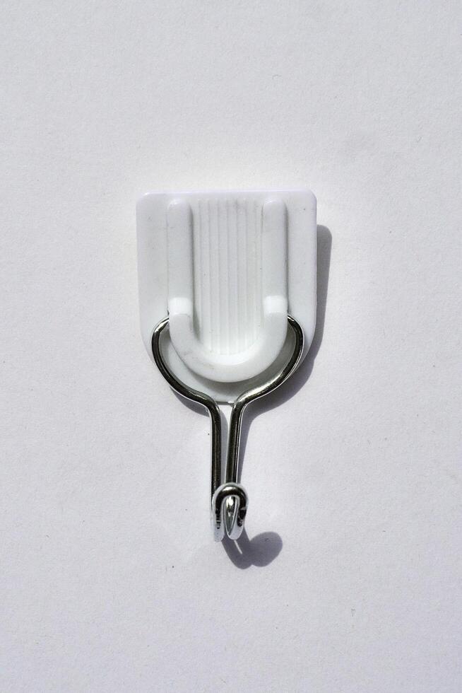 Adhesive wall hook for clothes or towel isolated on vertical white background from top angle view. photo