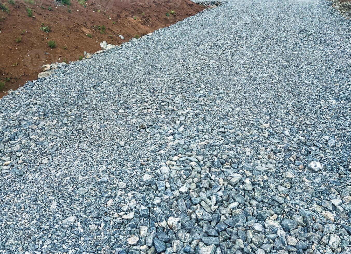 Gravel road surface with small stones and pebbles, leading through a natural landscape, showcasing the texture and composition of the gravel pathway in an outdoor setting photo