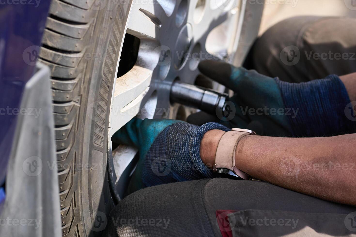 Repair car.Wheel mounting.Worker tightens nuts on wheel photo