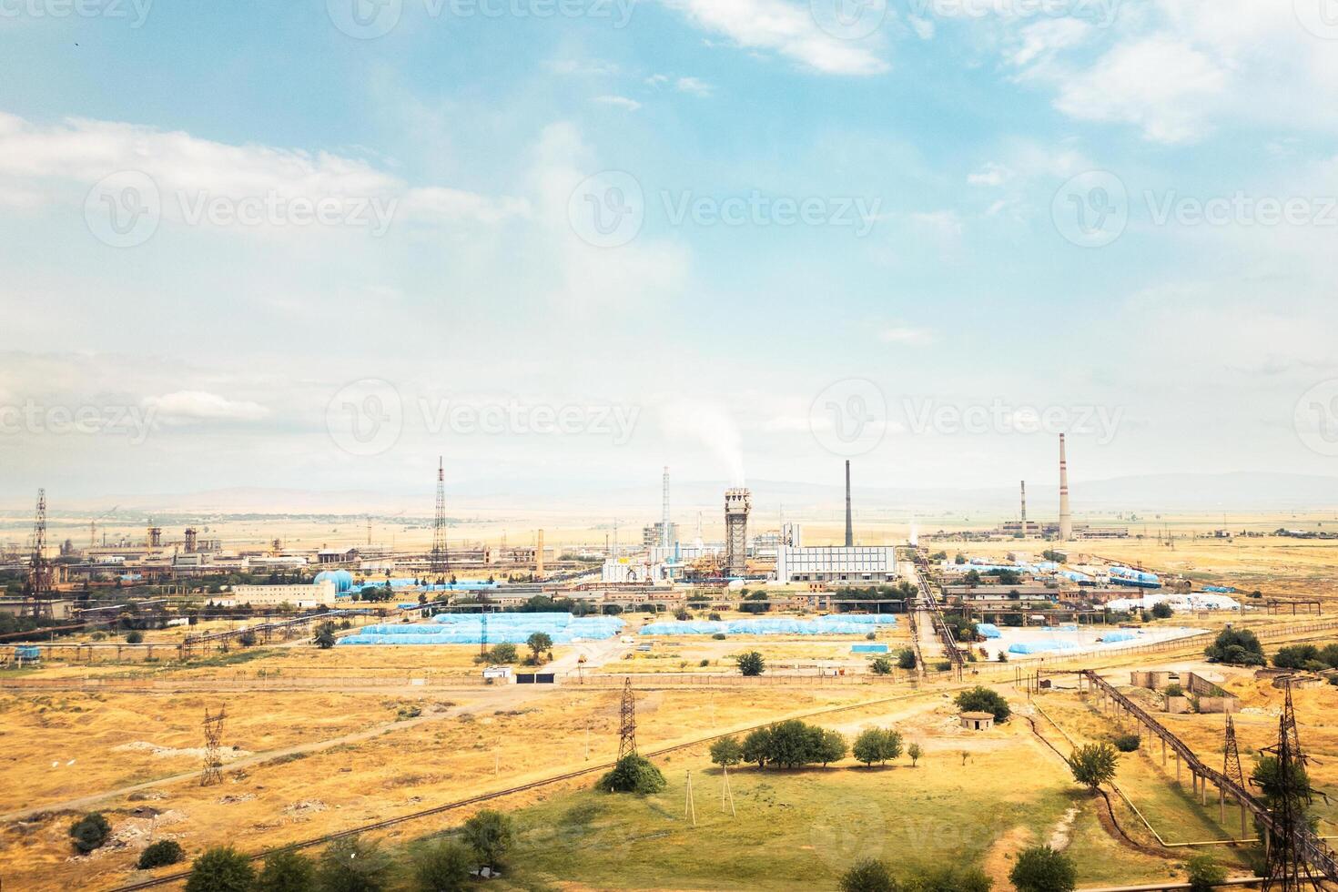 Aerial scenery Rustavi Azot factory complex in Georgia showing production buildings, storage tanks, tall chimneys emitting smoke, and extensive industrial infrastructure photo