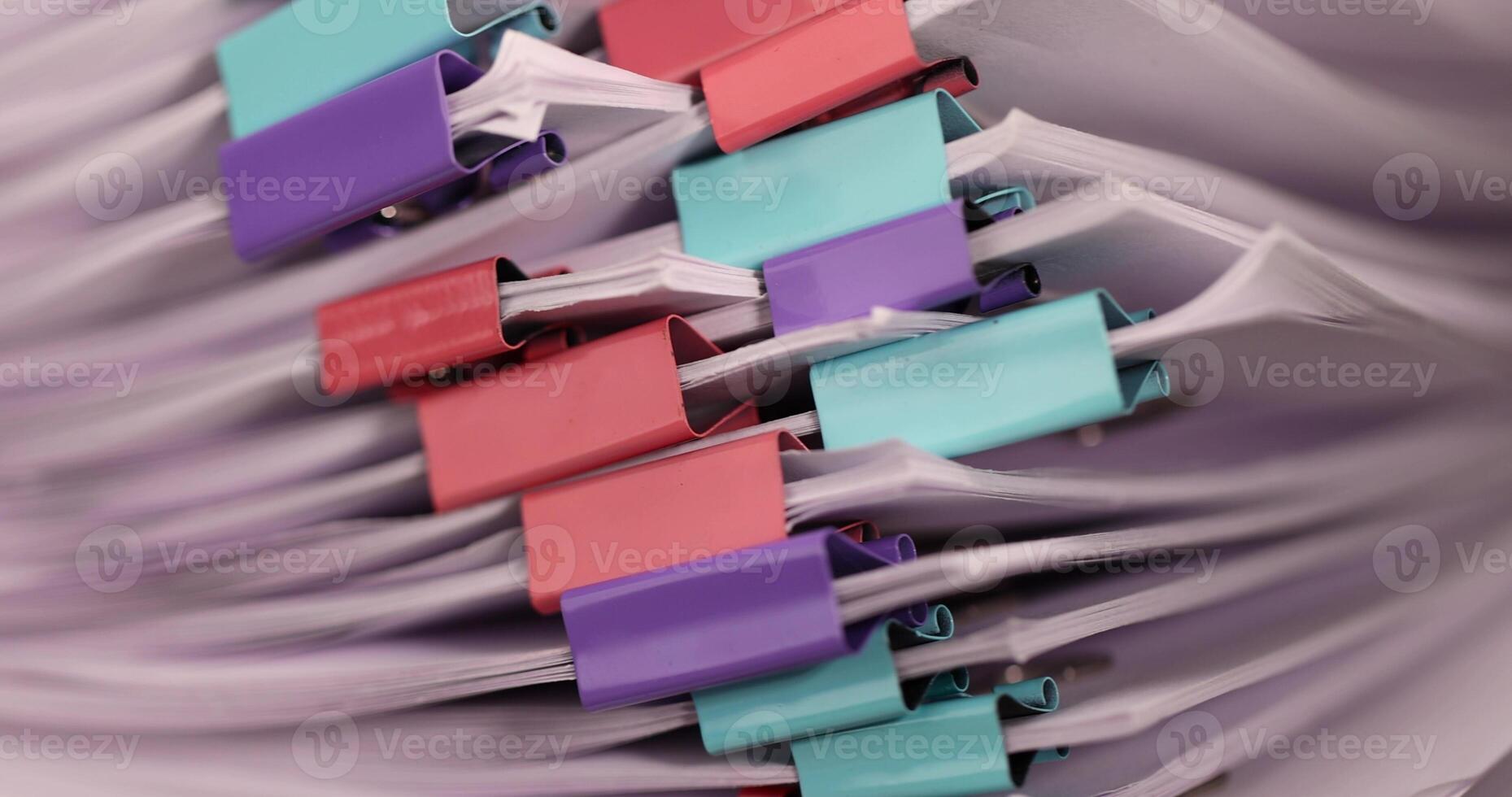 sheets of paper are connected by multicolored metal clips, stacked sheets of paper for documents are joined together photo