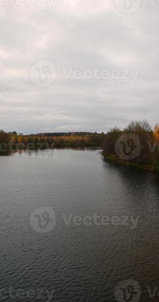 autumn landscape in cloudy weather with a lake and deciduous trees photo
