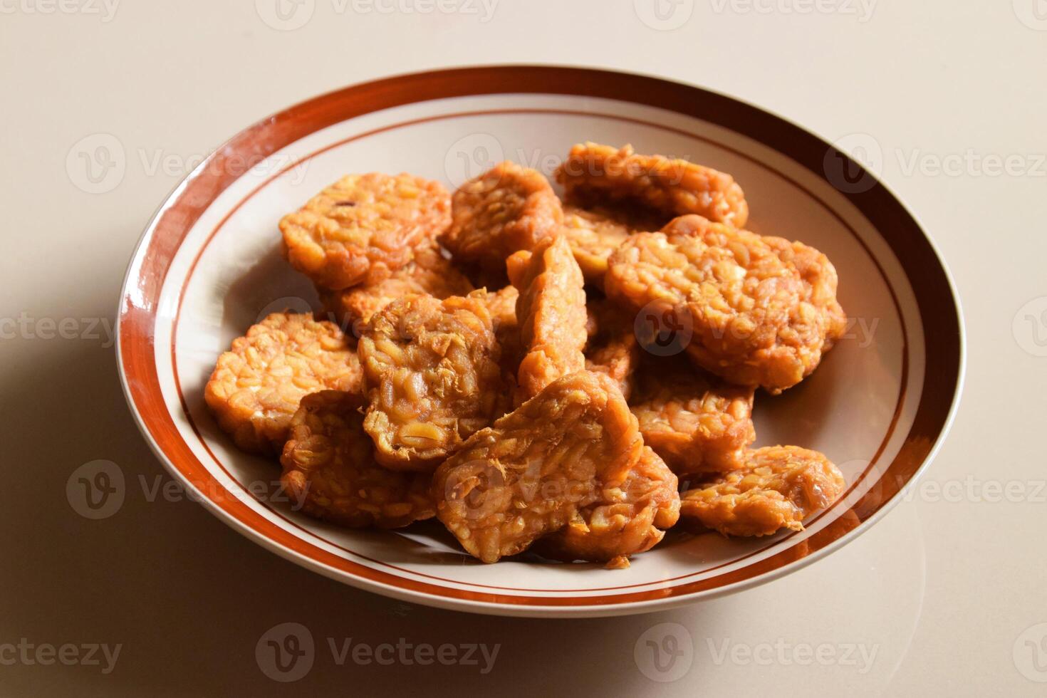 Fried tempeh on a plate with cream background photo