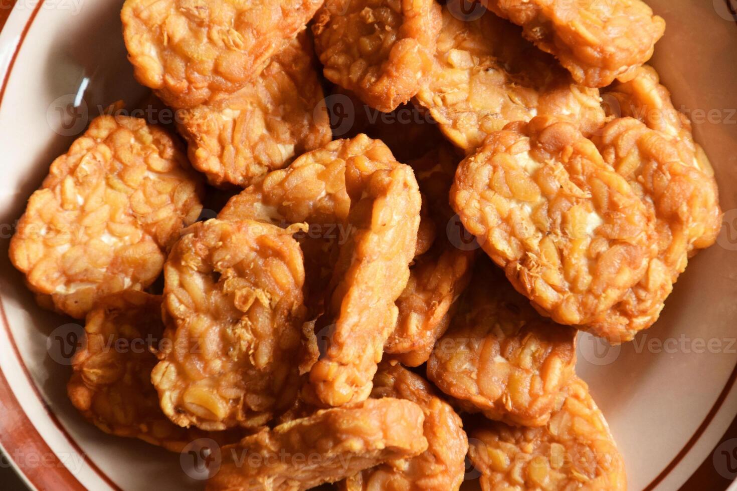 Tasty Indonesian tempeh dish on plate with simple cream backdrop photo