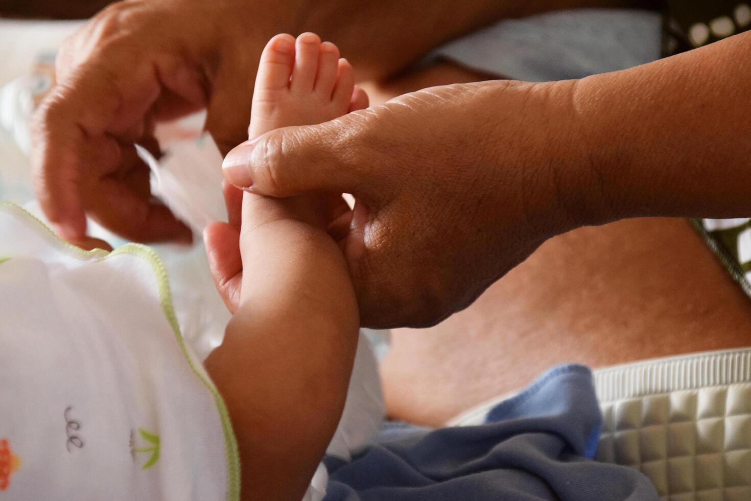 Asian mother gently cleaning her babys feet with love photo
