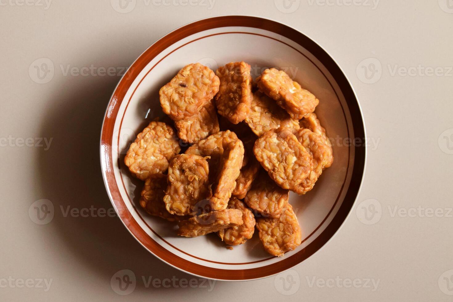 Indonesian fried tempeh viewed from above on cream background photo